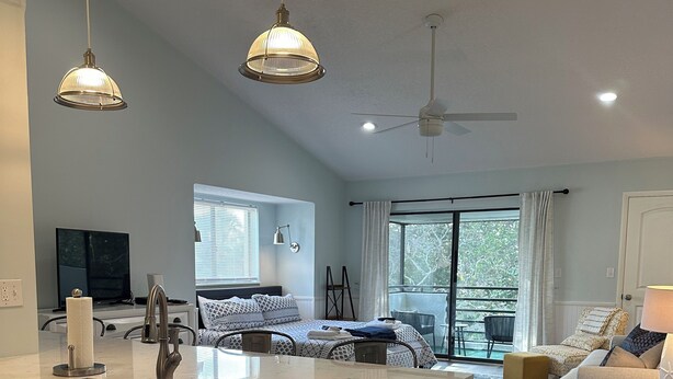 A modern kitchen with a large island, a dining area with a sofa, and a bedroom with a bed and window. - Beautiful remodeled studio across street to ocean SAWGRASS BEACH VILLAS (Sawgrass)