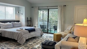 A bedroom with a bed, a ceiling fan, a window with blinds, a nightstand, a lamp, and a view of the outdoors. - Beautiful remodeled studio across street to ocean SAWGRASS BEACH VILLAS (Sawgrass)