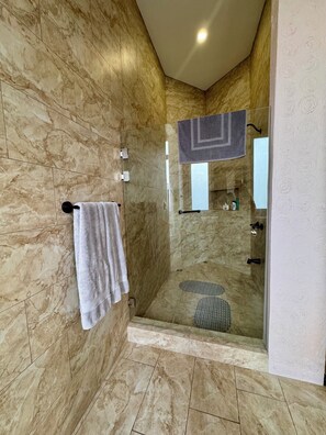 A modern bathroom with a glass-enclosed shower, marble walls, and a towel rack. - Escape the Cold- 2BR Mountain View Villa (Alajuela)