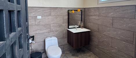 A bathroom with a toilet, sink, and decorative light fixture.