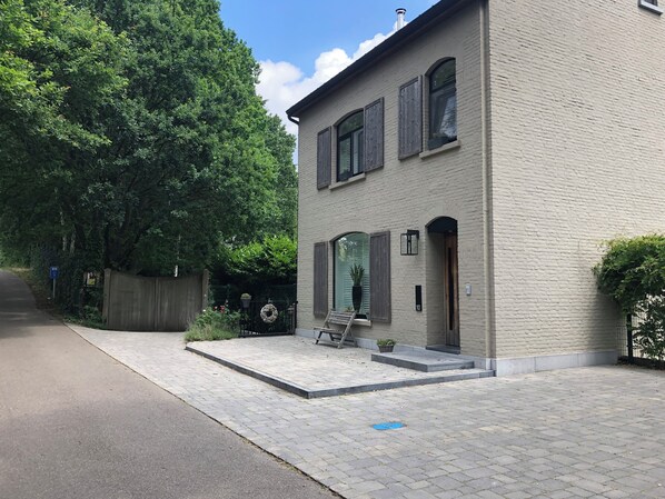 Een gebouw met twee verdiepingen, een verharde oprit en een houten omheining.