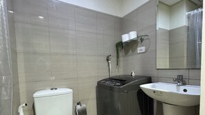 Un baño pequeño con inodoro, lavadora, lavabo y espejo.