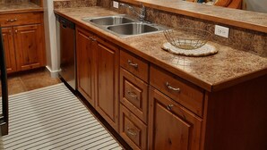 Eine Küche mit Holzausstattung, einer Granit Arbeitsplatte, einer Spüle und einem eingebauten Backofen.