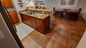 Eine moderne Küche mit Granit-Arbeitsplatten, Holzschränken, einer integrierten Spüle und einem Essbereich mit Holztisch und Stühlen.