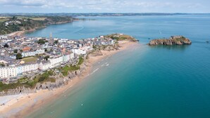A coastal town with a prominent church, sandy beaches, and a rocky outcrop. - 6 Paragon Court - Sea Front Apartment (Tenby)