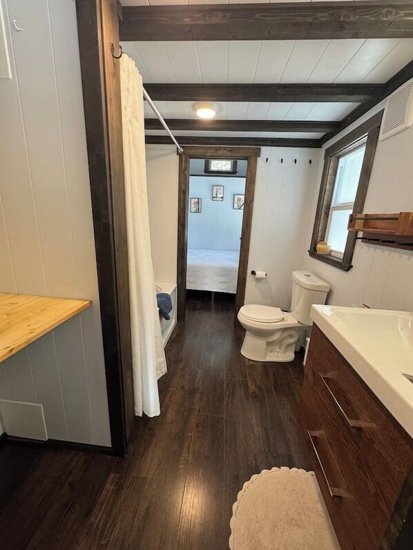 A compact bathroom with a wooden vanity, a toilet, and a bathtub.