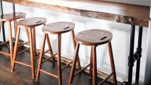 Een bar met een houten toonbank en vier krukken.