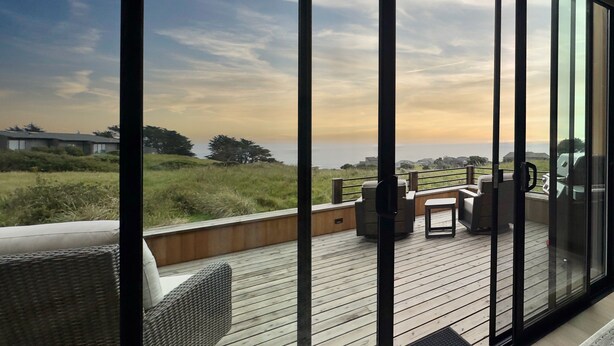 A deck with outdoor furniture, a view of the ocean, and a clear sky. - Sea Legacy | New Construction, Ocean View, Hot Tub (Sea Ranch)