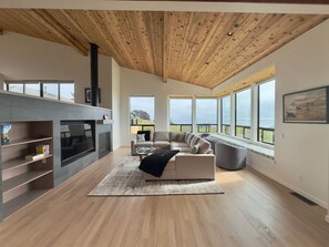 Ein modernes Wohnzimmer mit Kamin, einer Couch und großen Fenstern mit Blick.