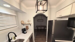 Una cucina moderna con frigorifero in acciaio inossidabile, forno a incasso, lavandino e macchina per il caffè.