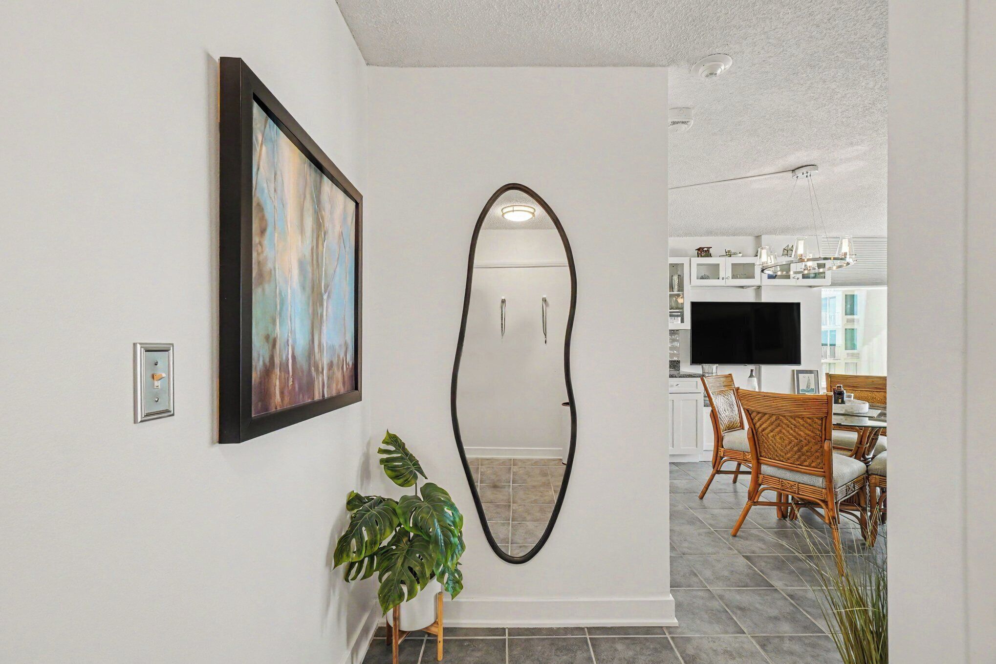 A modern interior with a dining area, a large mirror, and a framed artwork on the wall.