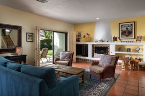 Ein Wohnzimmer mit einer Couch, Sesseln, einem Couchtisch und einem Kamin.