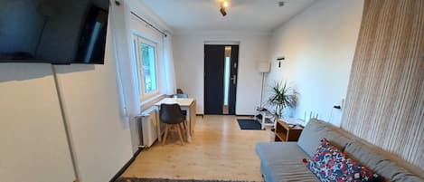 Un espacio habitable compacto con kitchenette, sofá, escritorio y silla.