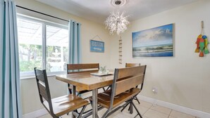 A dining area with a wooden table and chairs, a chandelier, a beach sign, and a painting of a beach scene. - 5 Mi to Beaches! Family Home in Fort Lauderdale (Fort Lauderdale)