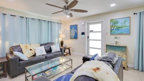 A living room with a sofa, a coffee table, a ceiling fan, and a painting on the wall. - 5 Mi to Beaches! Family Home in Fort Lauderdale (Fort Lauderdale)