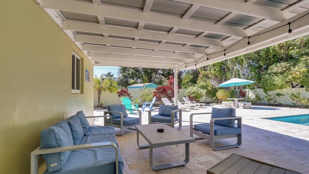 A covered outdoor seating area with a pool, lounge chairs, and umbrellas. - 5 Mi to Beaches! Family Home in Fort Lauderdale (Fort Lauderdale)