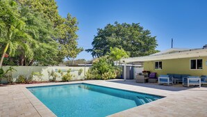 A rectangular swimming pool with a tiled deck, surrounded by greenery and a building with outdoor seating. - 5 Mi to Beaches! Family Home in Fort Lauderdale (Fort Lauderdale)