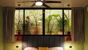 A bedroom with a bed, a ceiling fan, a window with plants, and two bedside tables. - House in Merida near Parque de las Americas. (For families and couples) (Mérida)