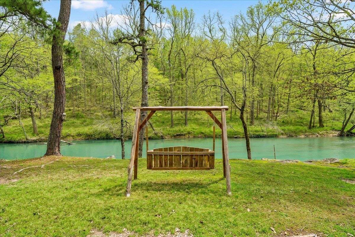 A wooden swing set in a grassy area with a river in the background.