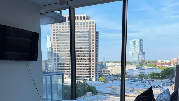 Un dormitorio con una cama grande, un ventilador de techo y vistas a edificios de la ciudad.