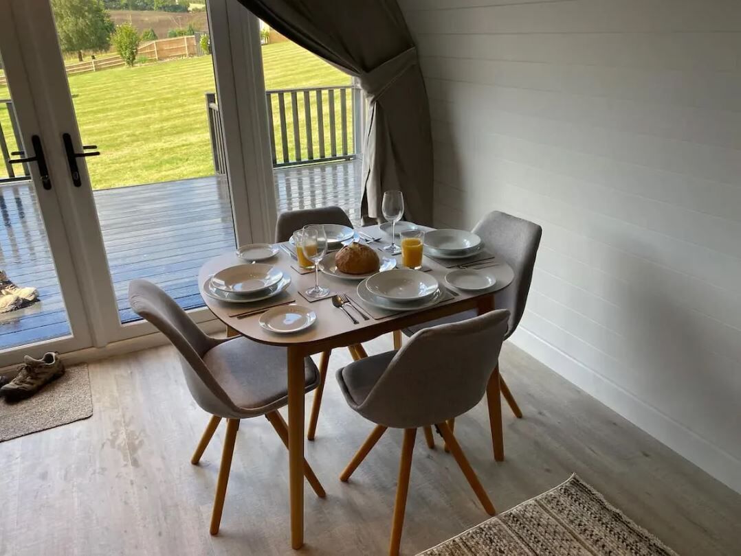 A dining table set for four with plates, glasses, and a loaf of bread.
