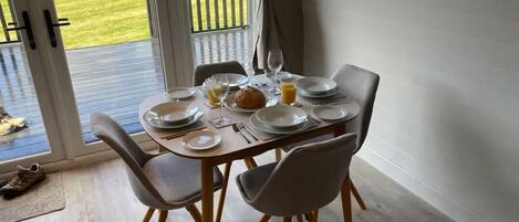 A dining table set for four with plates, glasses, and a loaf of bread.