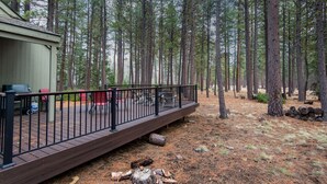 Eine Holzterrasse mit Metallgeländer, umgeben von hohen Kiefern.