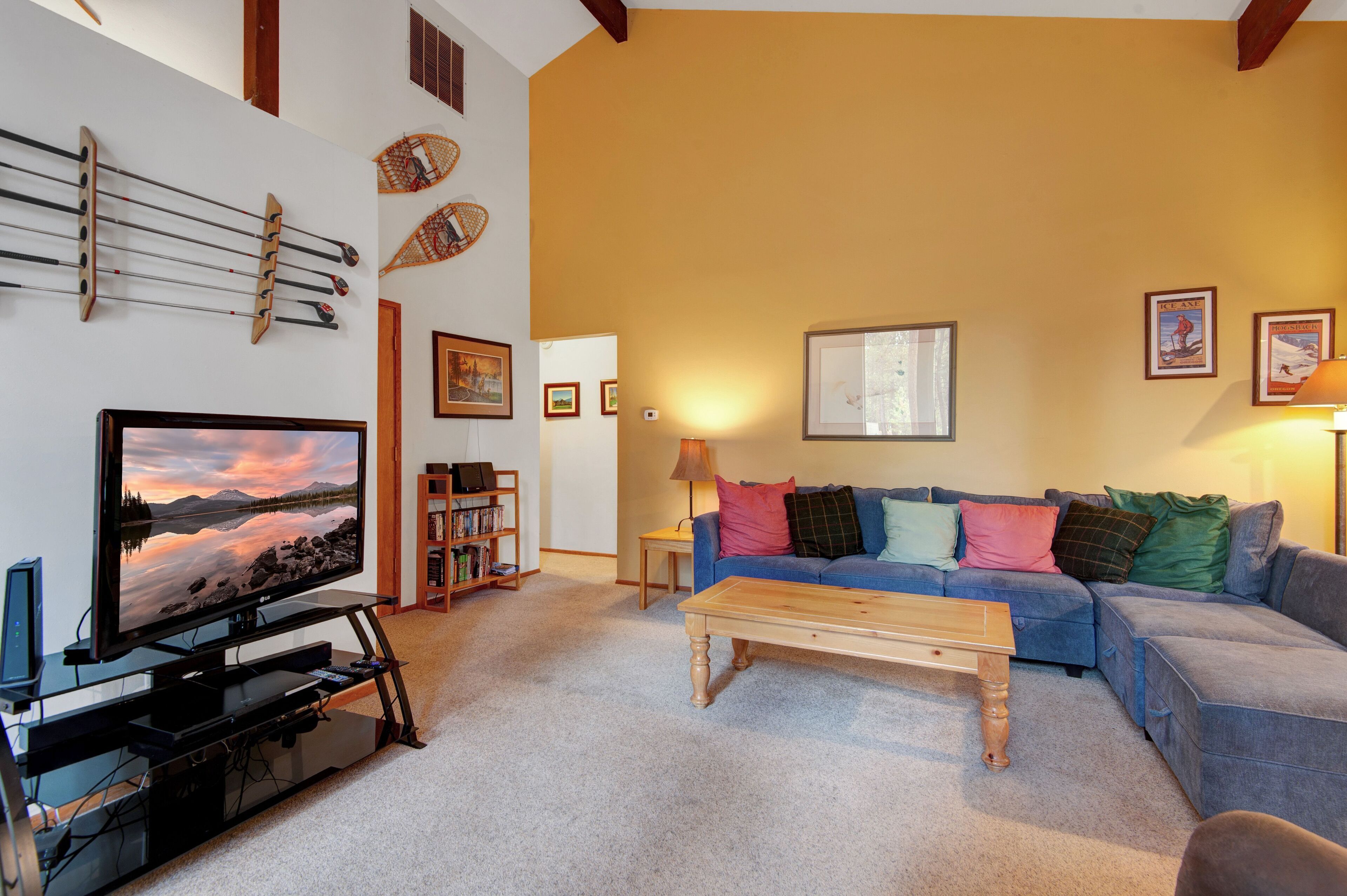 Ein Wohnzimmer mit Fernseher, Sofa, Couchtisch, Bücherregal und Wanddekorationen.