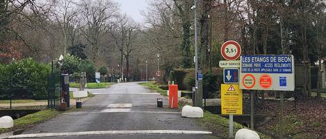 A road leading into a residential area with a speed limit sign of 30 km/h, a sign indicating private domain access, and bollards along the road.