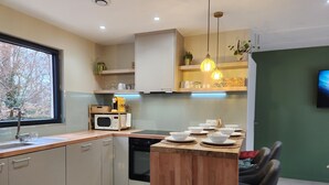 A modern kitchen with a wooden island, built-in appliances, and pendant lighting.