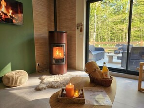 A modern room with a wood-burning stove, a comfortable seating area, and a view of the outdoors.