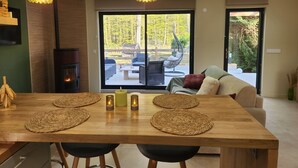 A dining area with a wooden table, woven placemats, candles, and a view of an outdoor patio with furniture.
