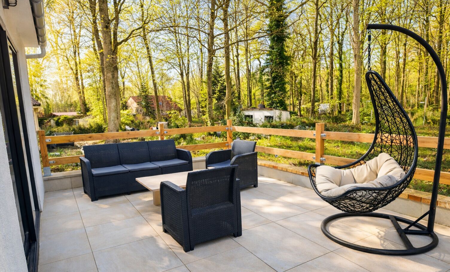 An outdoor patio with a sofa, chairs, and a hanging chair.