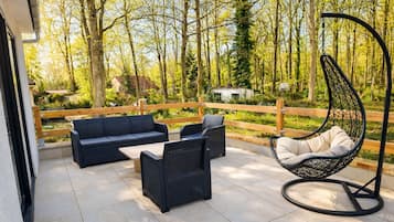 An outdoor patio with a sofa, chairs, and a hanging chair.