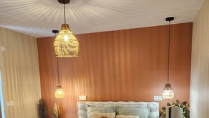 A modern bedroom with a large bed, two hanging lights, and a wooden accent wall.
