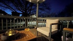 A wooden deck with a chair and a table, a railing, and a view of the street at night. - Modern Spa Hot Tub Lake Access Clean townhome (Cleveland)