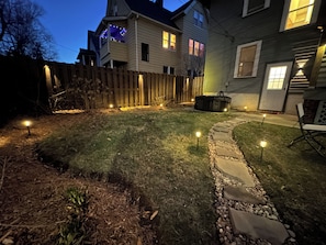 A backyard with a wooden fence, a stone pathway, and a lawn.