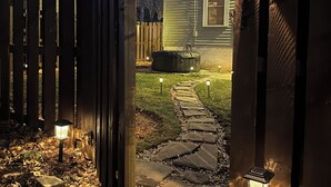 A stone pathway leading to a wooden gate, with a house in the background and a small garden area. - Modern Spa Hot Tub Lake Access Clean townhome (Cleveland)