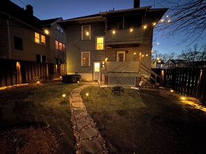 A two-story house with a stone pathway leading to a patio area.