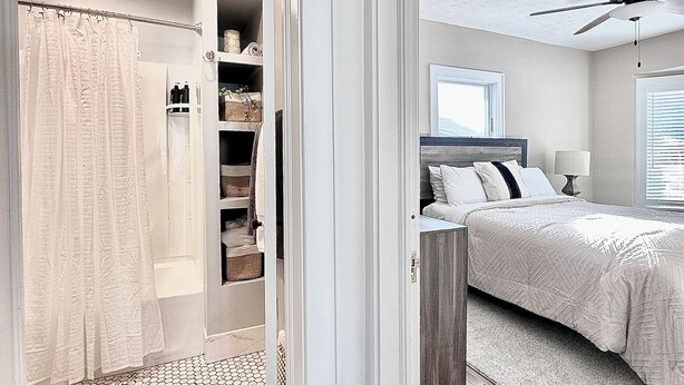 A bedroom with a wooden floor, a bed with a white comforter, a ceiling fan, and a window with blinds. - Modern Spa Hot Tub Lake Access Clean townhome (Cleveland)