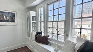 A room with a bay window, a framed picture on the wall, and a window seat with cushions and a vase. - Modern Spa Hot Tub Lake Access Clean townhome (Cleveland)