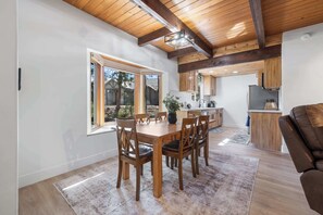 Eine moderne Küche mit Holzschränken, einer zentralen Kochinsel und einem Essbereich mit Holztisch und -stühlen.
