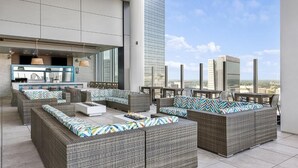 Un lounge sul tetto con mobili in vimini e una zona bar.