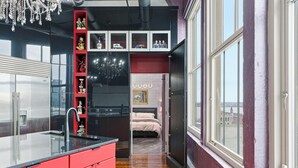 A modern kitchen with a red cabinet, a black countertop, and a decorative shelf with various items. - Luxury Penthouse Near Yum Center + Parking
  (Louisville)