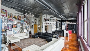 A spacious living room with a large sectional sofa, a chandelier, and a variety of artwork on the walls. - Luxury Penthouse Near Yum Center + Parking
  (Louisville)