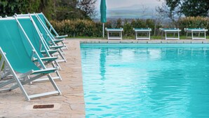 Un área junto a la piscina con sillas de descanso y vistas al paisaje.