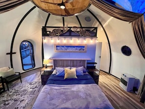 A cozy, circular room with a bed, a small table, and a chair. - Aurora Igloo w/ Hot Tub & Firepit near town. (Fairbanks)