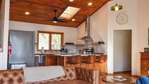 Uma cozinha moderna com uma ilha central, uma área de jantar com sofá de couro marrom e um ventilador de teto.