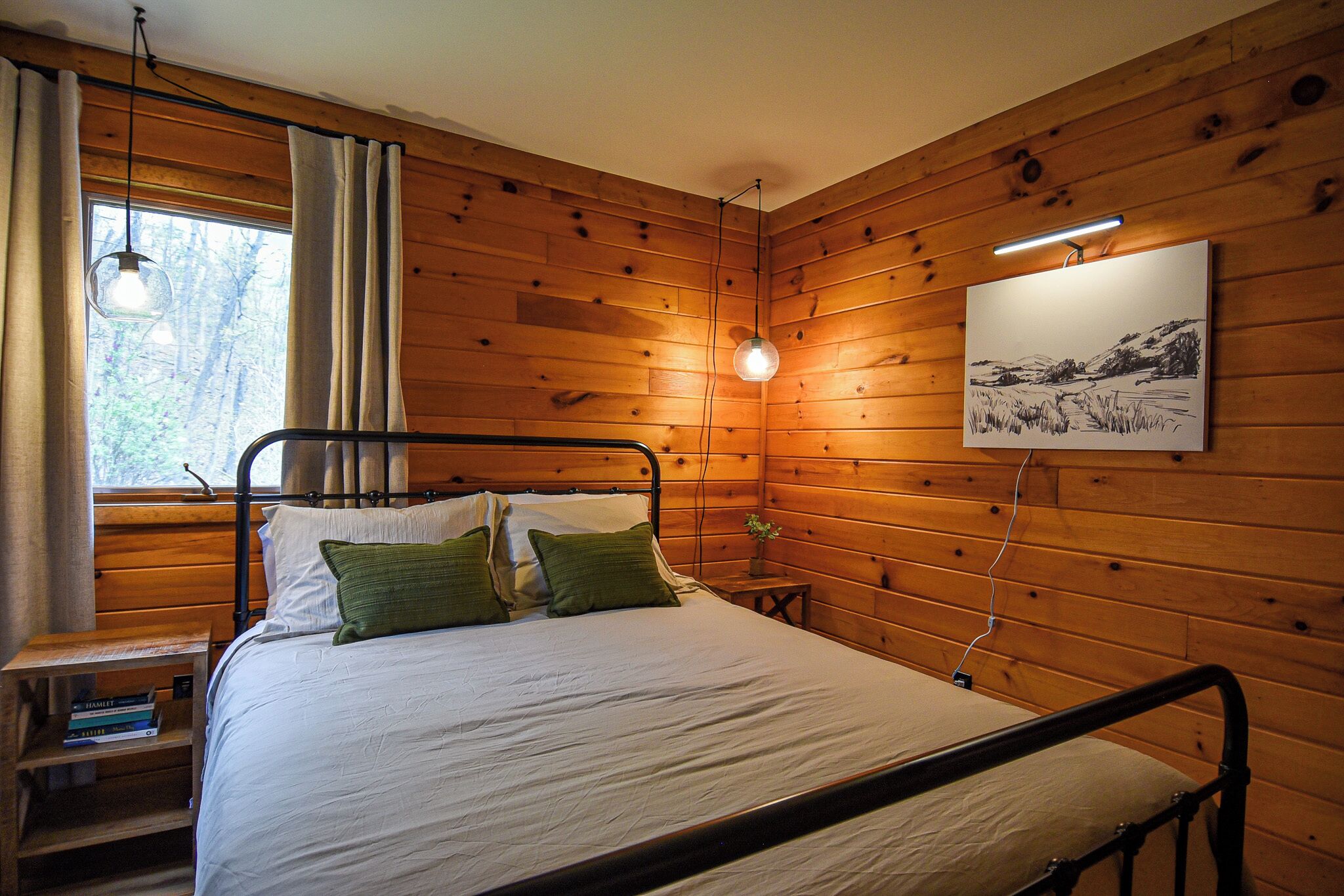 Habitació amb panells de fusta, un llit, una taula de nit, una làmpada i un quadre al mur.