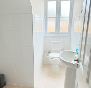 Een douche, handdoeken, zeep, toiletpapier